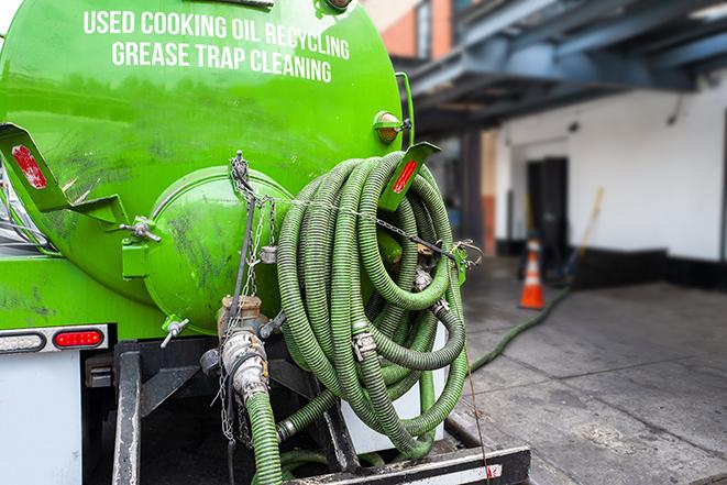 worker pumping grease trap at commercial kitchen in Coulee City